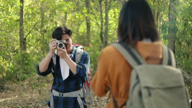 A boyfriend taking a photo of a girlfriend in the forest on sunny beautiful summer enjoys the vacation lifestyle.