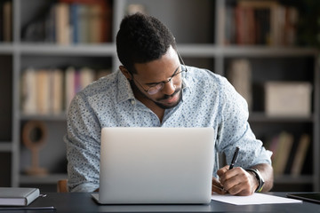 Focused african business man make notes study work on laptop
