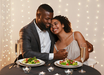Handsome african man hugging his girlfriend while festive dinner