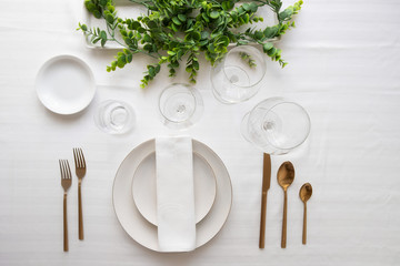 Elegant table setting,  white plates,  gold cutlery,  wine glasses and centrepiece . Tableware and...
