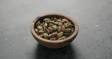 peeled pistachios in olive bowl on terrazzo surface