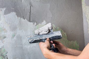 Plaster the wall with a putty knife.Internal construction and finishing works.The Builder puts...