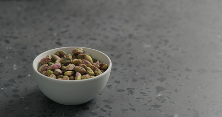 peeled pistachios in white bowl on terrazzo surface