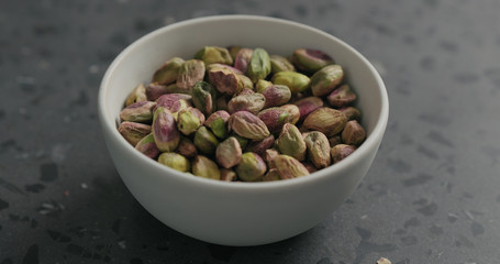 peeled pistachios in white bowl on terrazzo surface
