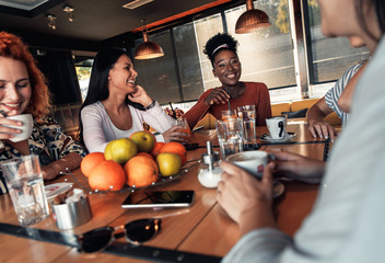 Group of young female friends having fun in cafe talking and laughing while sitting at table.	