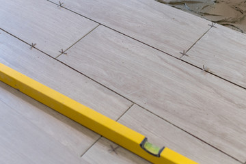 Close up shot of a metal yellow spirit level placed on a newly installed yet not finished kitchen tiles