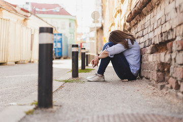 Depressed young woman sitting down with her head on her knees