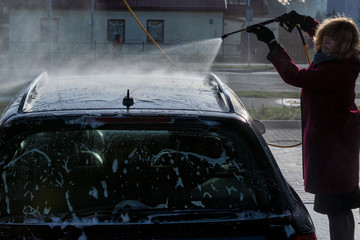 Woman washing car in self-service car wash.