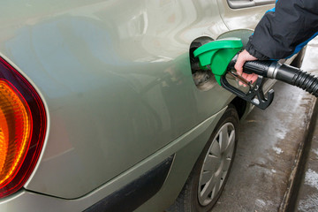 Detail view of hand holding fuel nozzle at petrol station.