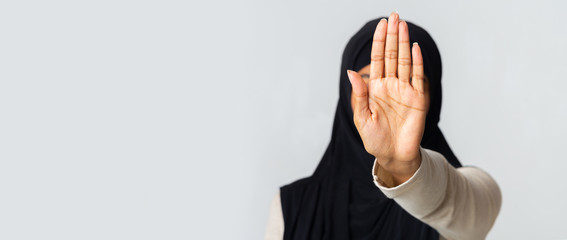 Unrecognizable muslim woman in hijab making stop gesture with hand