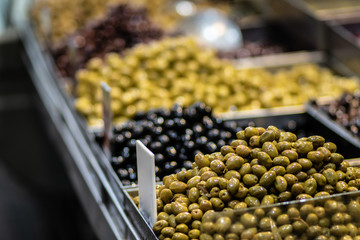 Pickled, brown, black, green, and red olives. Authentic Middle Eastern and Syrian style. Against a blurry background. For Sale in Old Market, Jerusalem.