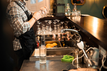 Bearded young bartender is washing a glass