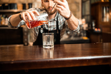 Male bartender pouring fresh cocktail in fancy glass