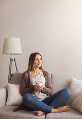 Positive millennial woman relaxing with coffee at home