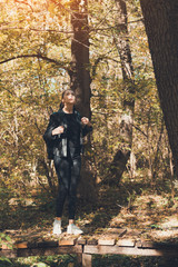 Young woman walking in the autumn forest alone. Vertical frame