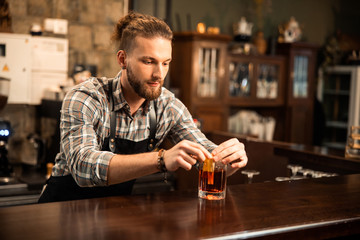 Bearded young barman is completing cocktail making