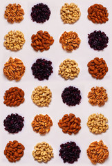 Seamless pattern of round dots of nuts (cashew, peanuts, almonds, walnuts), cranberry on light background.