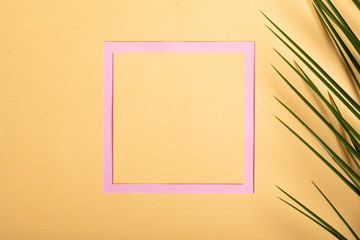 Summer travel concept. Tropical beach travel vacation concept. Abstract trendy yellow summer flat lay on pink background with green palm leaves.