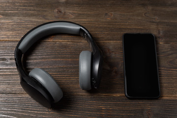 Phone and headphones on wooden background. Listen to music and audiobooks.