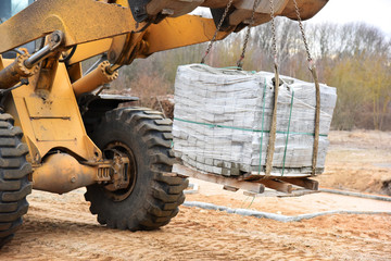 The tractor transports the pallet to the construction site, focus on the paving slabs.