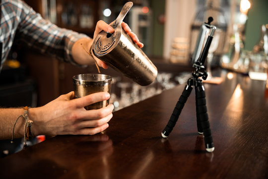 Close up of barman using mobile phone for his vlog