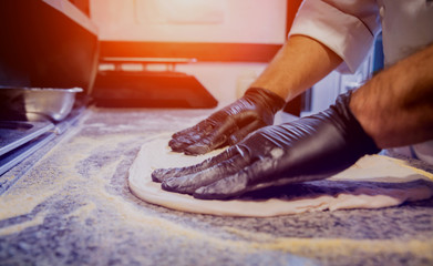 The process of making pizza. Hands of chef baker making pizza at cafe kitchen