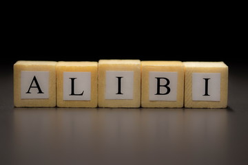 The word ALIBI written on wooden cubes isolated on a black background...