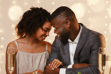 Afro couple in love cuddling at restaurant while having date