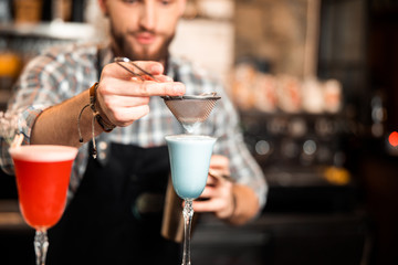 Bearded bartender finishing cocktail making at bar