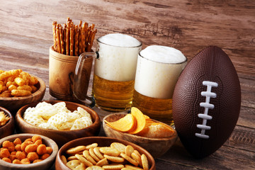 Fototapeta na wymiar Chips, salty snacks, football and Beer on a table. Great for Bowl Game snack projects.