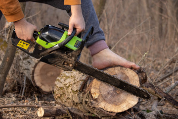 Logging with chainsaw with no equipment. Dangers of logging. Green chainsaw and bare foot cutting...