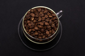 coffee beans in a glass mug on a black background.