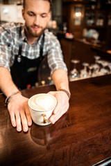Male barista giving mug of coffee to customer