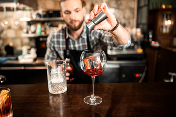 Young barman pouring alcohol into glass with ice