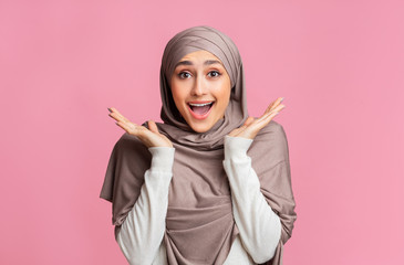 Portrait of excited young islamic girl in hijab exclaiming in amazement