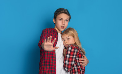 Elder brother embracing his little sister, protecting her from parents abuse