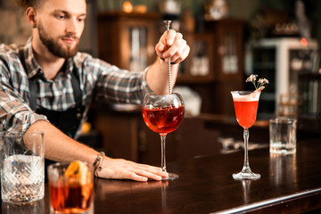 Young bartender making alcohol cocktail in restaurant