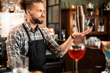 Smiling barman with shaker preparing cocktail at bar