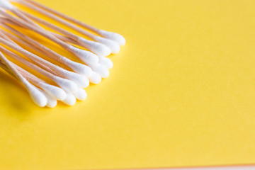 Medical cotton swabs on bamboo sticks on a yellow background. Hygiene of the human body. Environmentally friendly hygiene items.