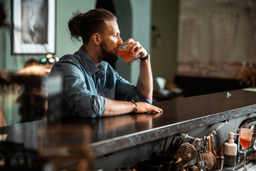 Young man is sitting at bar counter indoors