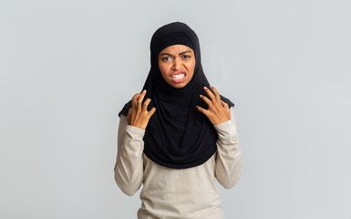 Annoyed black muslim woman emotionally gesturing with hands and grimacing