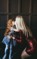 Mother congratulating her little redhead daughter on birthday. Cute child kissing mom.