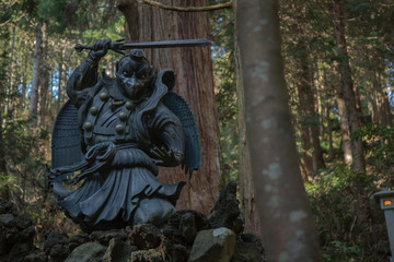 japanese mythology statue with sword on rocks
