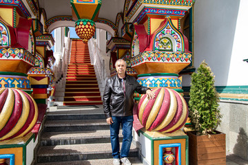 A man in a dark jacket on the background of decorative balls in the park