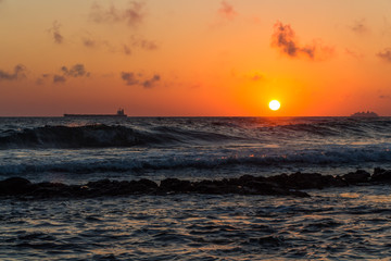 Beautiful sunset with the gold sun disk and red clouds is on the ocean beach