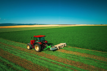 Fototapeta premium Tractor mowing green field