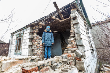 A boy in a ruined house, a teenager was left homeless as a result of military conflicts and natural disasters.