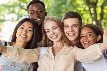 Happy friends taking selfie while walking in park