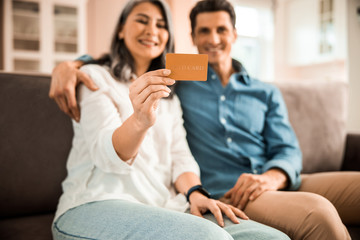 Happy pretty woman holding payment card at home