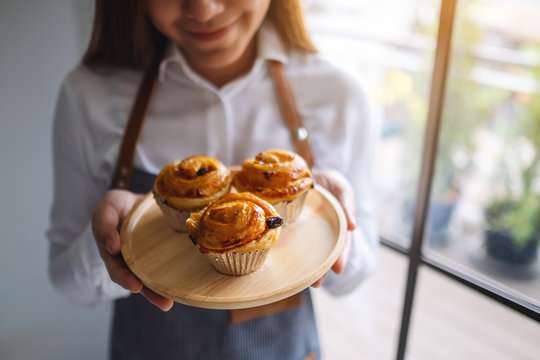 A waitress holding a wooden plate of raisin danish